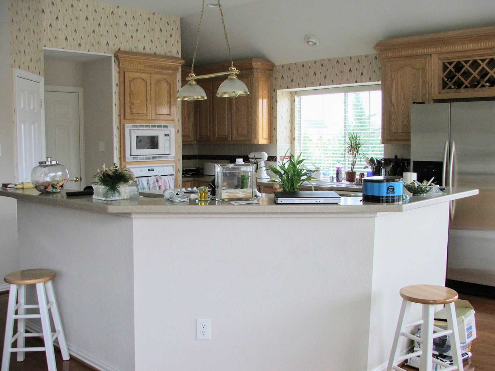 Before: oak-cabinet kitchen with a laminate-topped peninsula and wallpapered walls